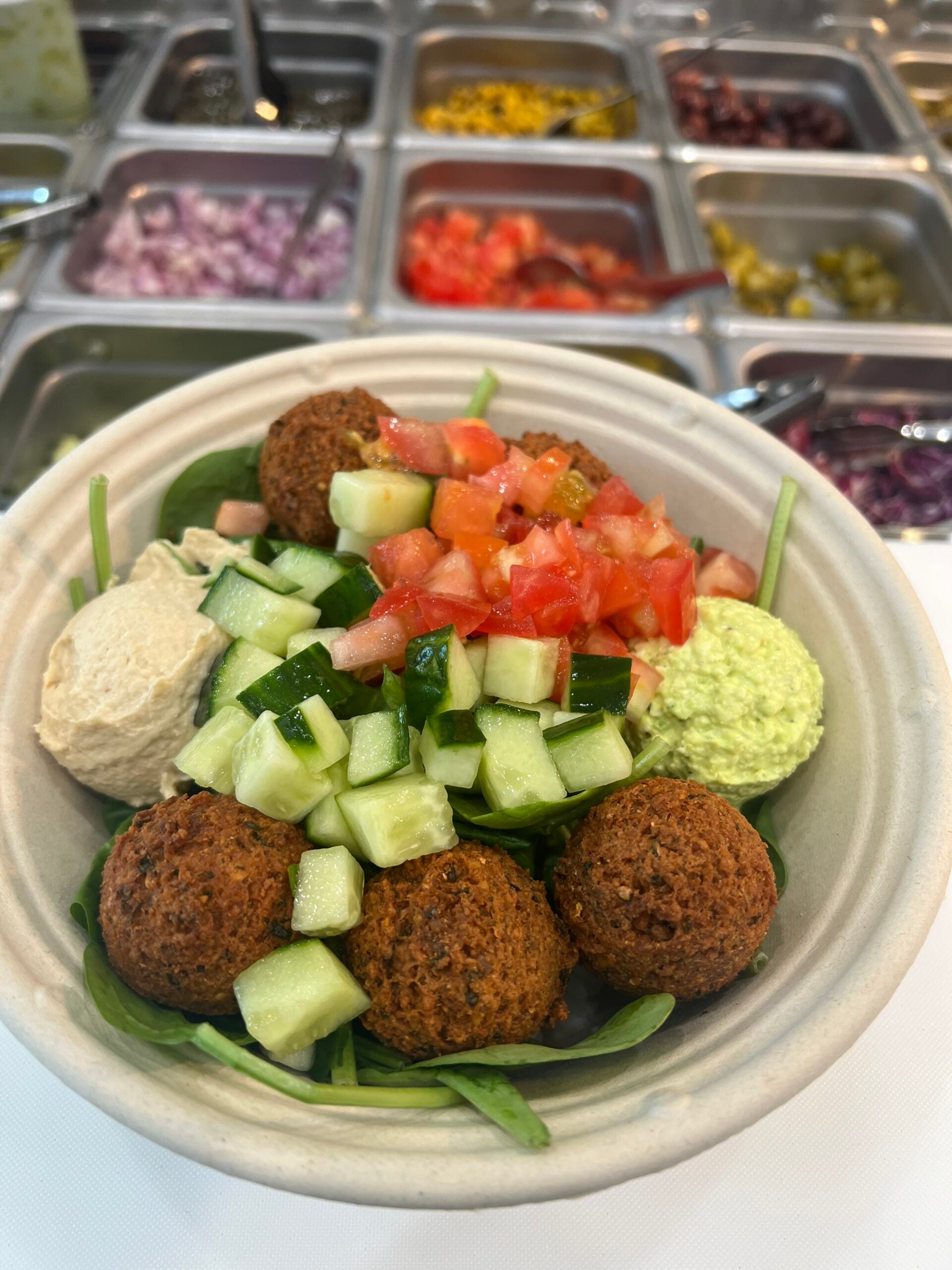Why Owning a Business That Reflects Your Culture Changes Everything A proud restaurant owner standing behind a fresh Mediterranean counter — the kind of business that represents your heritage every single day.